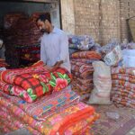 A vendor arranging and displaying quilts to attract the customers for selling at Factory Area