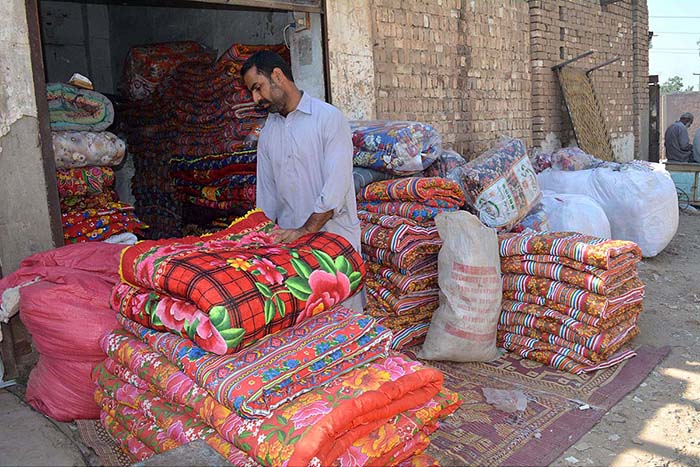 A vendor arranging and displaying quilts to attract the customers for selling at Factory Area