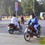 A female student riding motorcycle while going to school at Rehman Plaza Chowk.
