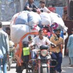 A motorcycle rickshaw puller is carrying scraps of old clothes to sell in the local market