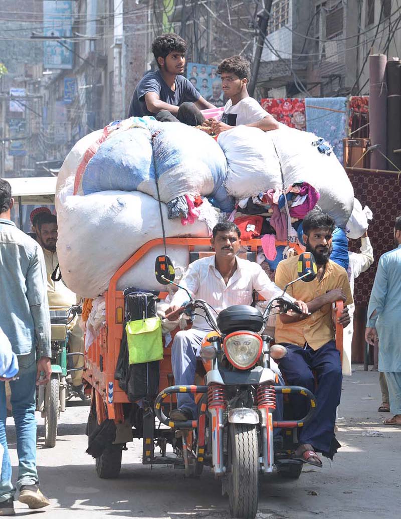 A motorcycle rickshaw puller is carrying scraps of old clothes to sell in the local market