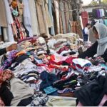 Woman selecting and purchasing used clothes at roadside