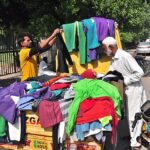 People selecting and purchasing warm clothes from roadside stall in front of Municipal Corporation.