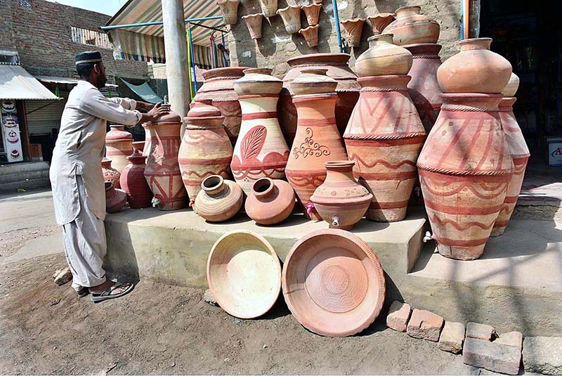 A vendor displaying clay made pots to attract the customers at Latifabad