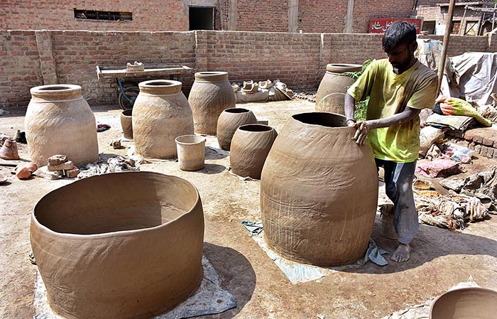 A worker busy in preparing the clay made pots at his workplace.