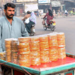 A vendor selling a traditional sweet item on his handcart.