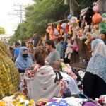 Women selecting and purchasing used clothes at roadside.