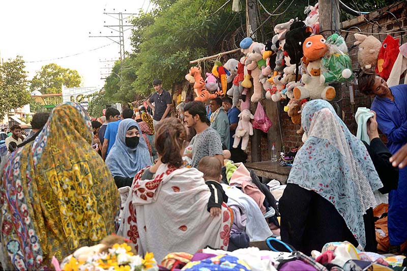 Women selecting and purchasing used clothes at roadside.