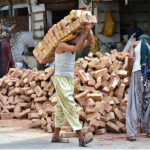 Labourers busy in shifting bricks during construction work of a house.