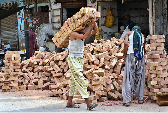 Labourers busy in shifting bricks during construction work of a house.