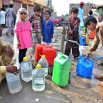 Children filling their pots with clean water from hand pump