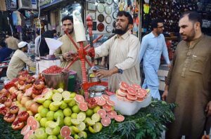 A vendor extracting pomegranate and grapefruit juices for customers at Qissa Khawani Bazaar
