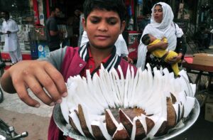 A young boy displaying and selling coconut at Gol chowk