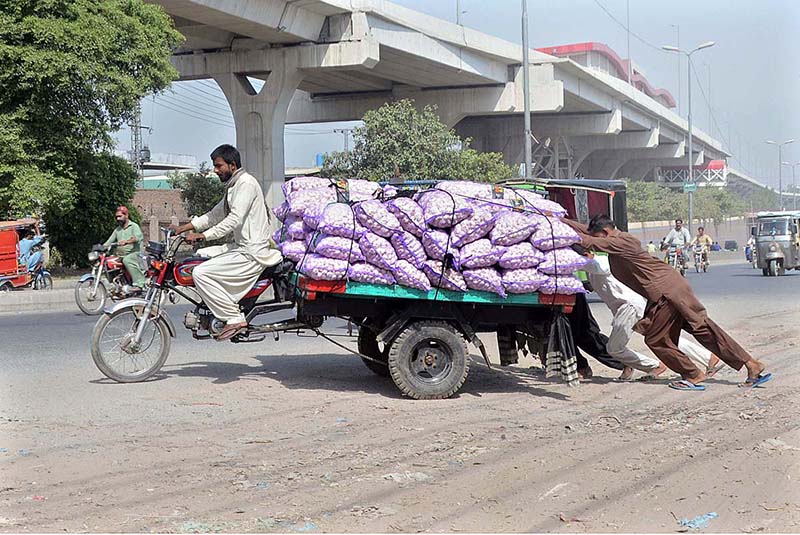 People pushing an out of order tricycle rickshaw loaded with