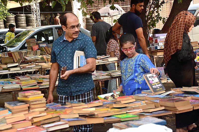 Customers are selecting old books from a roadside stall.