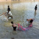 Youngsters busy in catching fish with the help of a piece of cloth and net from canal.