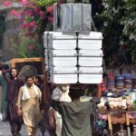 Laborer carrying iron suitcases on his head for selling in the market at Qissa Khawani Bazar.