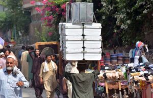 Laborer carrying iron suitcases on his head for selling in the market at Qissa Khawani Bazar.