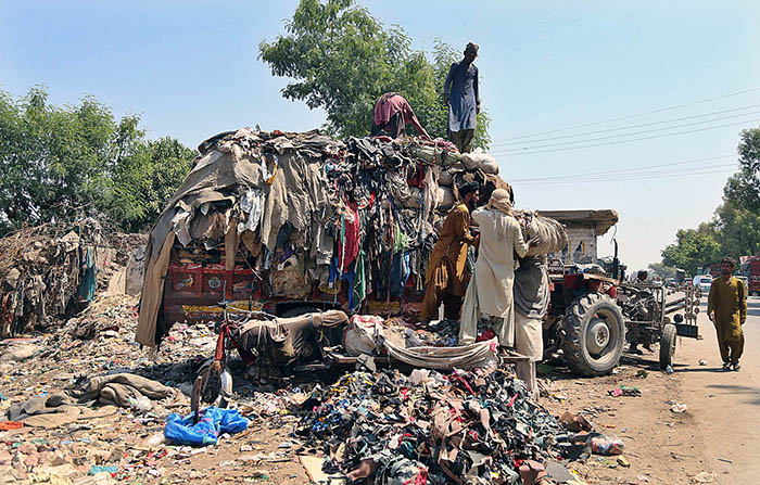 Labourer loading valuables on tractor trolley after collecting from garbage at Tando Yosuf Road.