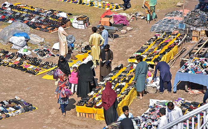 People busy in selecting and purchasing old shoes from vendors along Islamabad Expressway