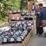 A motorcyclist purchasing a helmet from a roadside vendor in the city