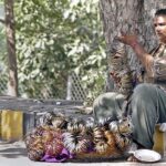A woman vendor displaying bangles to attract customers at her roadside setup.