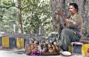A woman vendor displaying bangles to attract customers at her roadside setup.
