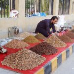 A vendor displaying dry fruit to attract customers at roadside setup.