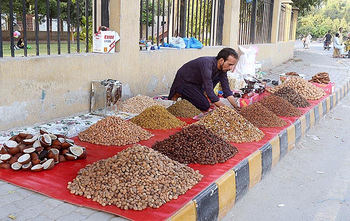 A vendor displaying dry fruit to attract customers at roadside setup.