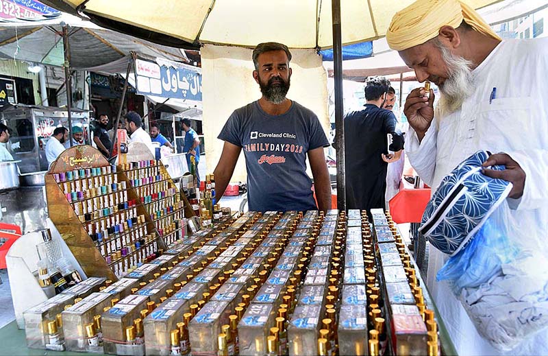 A person selecting local perfume (Itar) from vendor in a local market