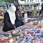 Customers are selecting old books from a roadside stall.