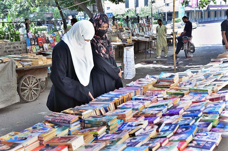 Customers are selecting old books from a roadside stall.