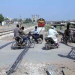 Motorcyclists crossing railway track while train approaching on the same track at Makki Shah Railway Crossing Gate