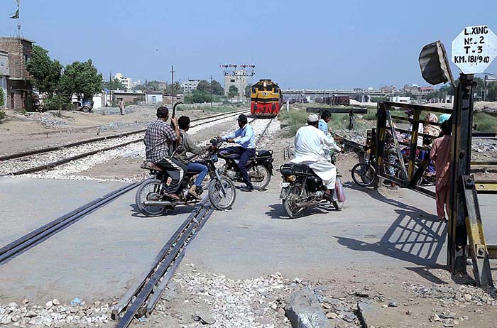 Motorcyclists crossing railway track while train approaching on the same track at Makki Shah Railway Crossing Gate