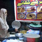A woman is preparing and selling homemade food on LOS Road as a means of earning a living.