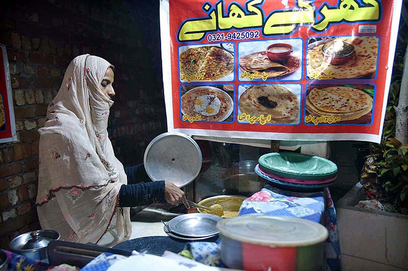 A woman is preparing and selling homemade food on LOS Road as a means of earning a living.