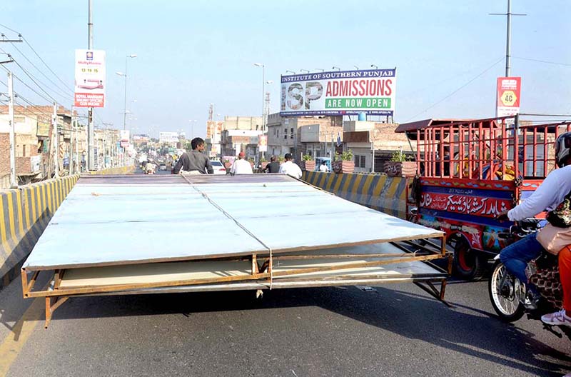 A tricycle rickshaw holder on the way loaded with Huge Billboards towards his destination creating a hurdle in the smooth flow of traffic needs the attention of concerned authorities