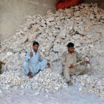 Labourers busy in crushing salt into tiny pieces at their workplace.