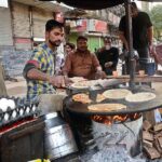 A vendor preparing the traditional food item paratha to attract the customers at his roadside setup in the Provincial Capital