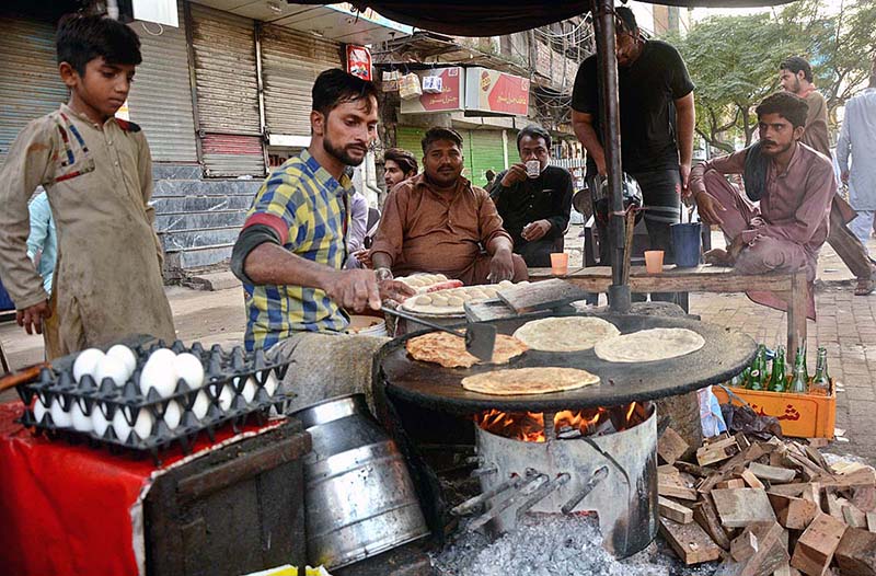 A vendor preparing the traditional food item paratha to attract the customers at his roadside setup in the Provincial Capital