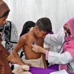 Lady Doctor examine a child in a medical camp during Health Week at THQ Hospital Chak no 90 SB