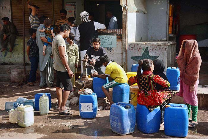 People filling pots with clean drinking water at hand pump.