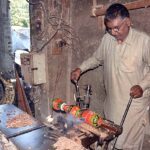 A carpenter busy in making part of a traditional bed (charpai) at his workplace.