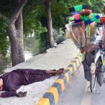 A street vendor enjoying nap on footpath after day long selling household items on his bicycle.