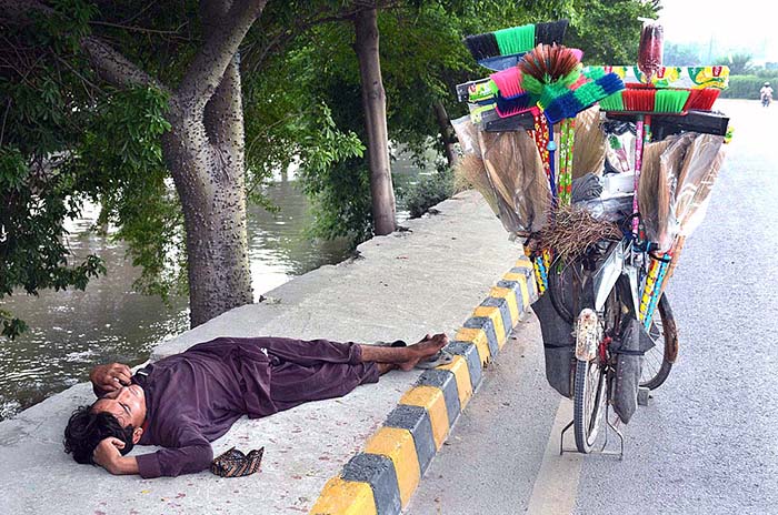 A street vendor enjoying nap on footpath after day long selling household items on his bicycle.