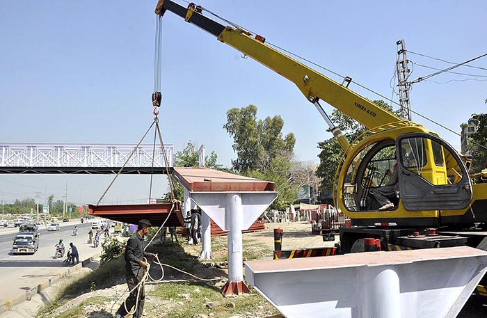A view of Construction work of newly install overhead bridge at Captain Karnal Sher Khan Shaheed Avenue.