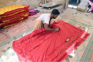 A worker busy in preparing quilt for upcoming winter season.