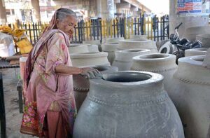 An elderly woman busy in preparing traditional oven “Tandoor” at her workplace.