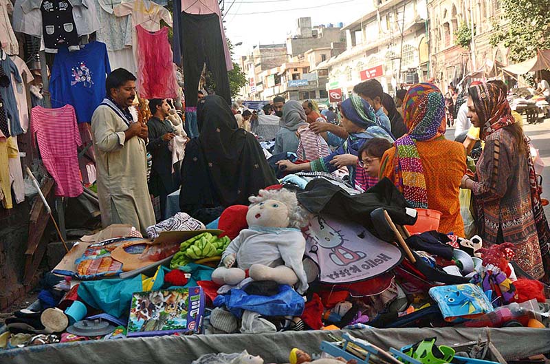 Women selecting and purchasing secondhand clothes displayed by roadside vendors