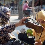 Women buying used shoes from a roadside stall.